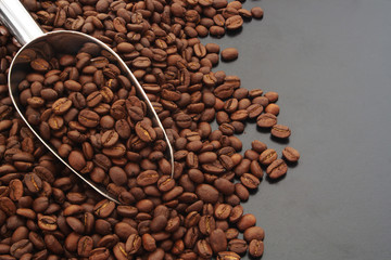 Roasted coffee beans and scoop on table