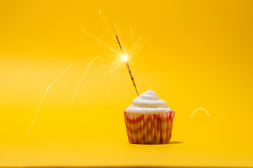 Birthday cupcake with firework on yellow background.