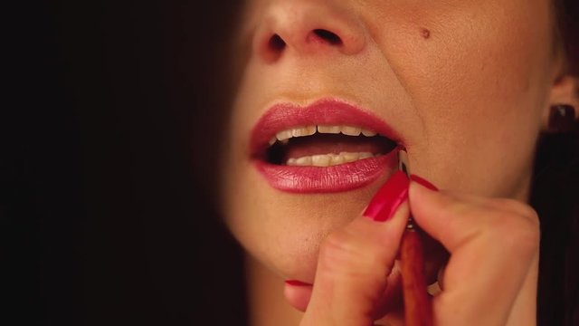 Process of making nice lip line on lips of woman.