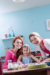 A family of three girls making pastry in a full color kitchen