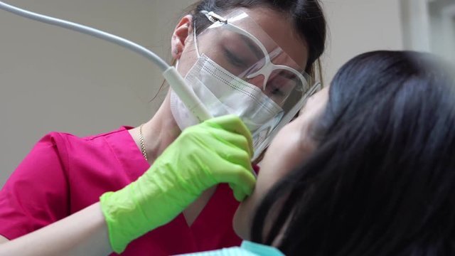 Woman at the dental hygienist getting professional tooth whitening and ultrasound cleaning. Shot in 4k