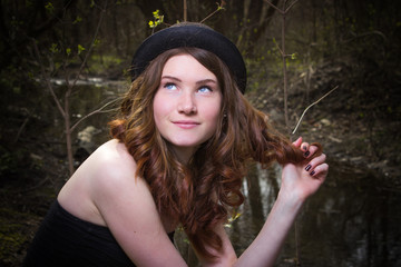 Cute young girl in a black hat. Red-haired girl. Yellow skirt. Girl In the woods