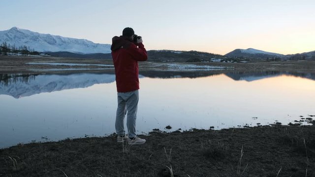 Young man taking a picture with DSLR in calm summer morning after night in red tent 20s 4k