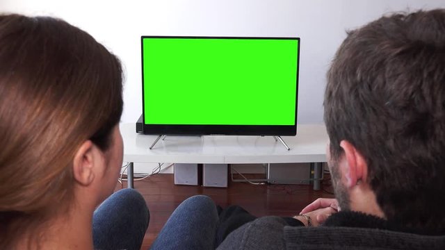 Couple Home Watching Green Screen TV. Couple watching television with green screen. Shot behind models shoulders