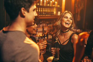 Young woman having drink at nightclub with friends - Powered by Adobe