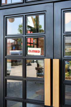 Closed sign board hanging on door of cafe.