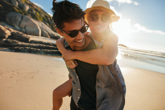 Boyfriend giving piggyback ride to girlfriend at beach