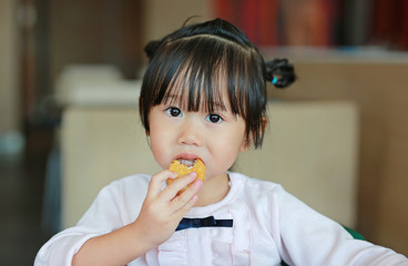 Close up of little asian girl eating fried chicken in cafe.
