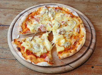 Delicious homemade pizza served on wood tray against wooden table