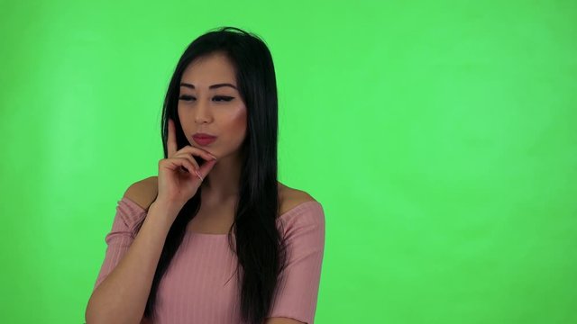young attractive asian woman thinks - green screen studio