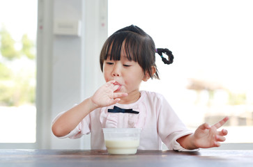 Little child girl eating and tasting ice cream, Child girl licking her fingers.