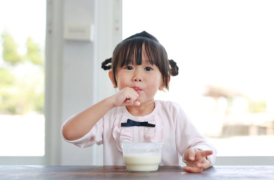 Little child girl eating and tasting ice cream, Child girl licking her fingers.