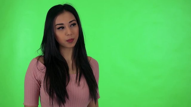 young attractive asian woman looks to distance - green screen studio
