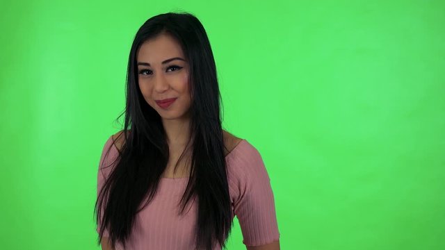 young attractive asian woman waves with hand - green screen studio