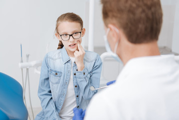 Worried girl explaining dentist where the pain is