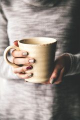 Close-up of a woman's hand holding a cup of hot coffee. fashion, leisure