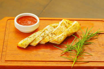 Delicious grilled chicken breast and ketchup with a small piece of romero spice on wooden board