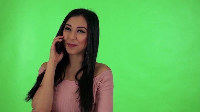 young attractive asian woman phone and smiles - green screen studio