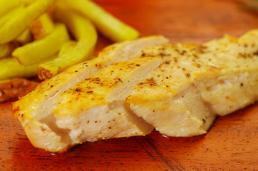 Well-done grilled marinated grilled chicken breast on wooden board