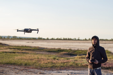  picture of black flaying quadrocopter dron and pilot siluette in sunset light background, tourist use dron helicopter to photography or filming desert landscapes 