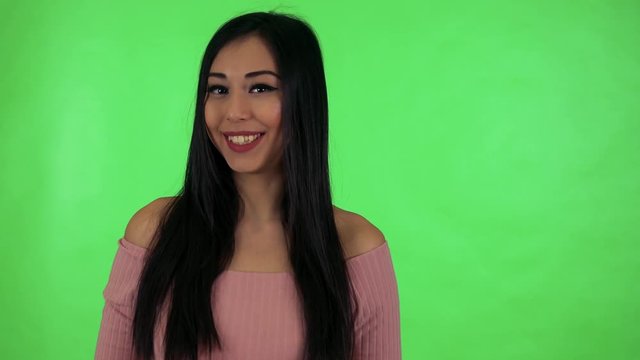 young attractive asian woman talks to camera - green screen studio