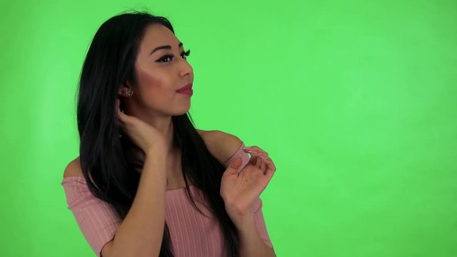 young attractive asian woman adjusts her clothes - green screen studio