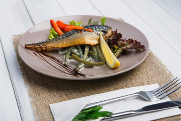Restaurant food on wooden table. Smoked mackerel with vegetables closeup