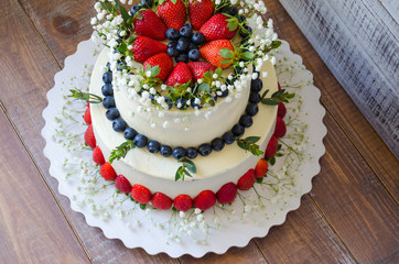 two-tier cream cheese wedding cake with blueberries and strawberries