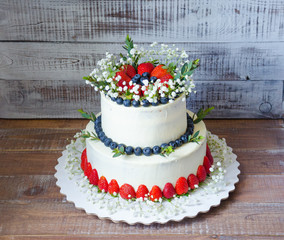 two-tier cream cheese wedding cake with blueberries and strawberries