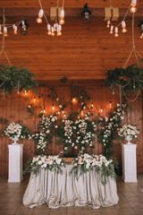 Wedding table banquet decorated with flowers and plants, retro lamps on a wooden background