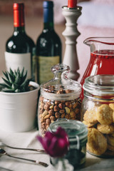 Glass jars with hazelnuts, biscuits and mors, flower pot and bottle of wine © Alexandra