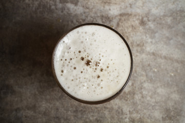 Vaso de Cerveza con espuma sobre fondo de mesa gris. Vista superior