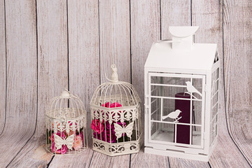 Farol blanco con vela y jaulas con flores.