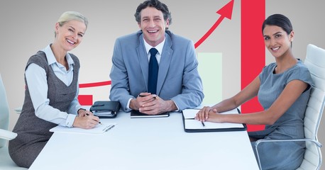 Happy business people at desk against graph