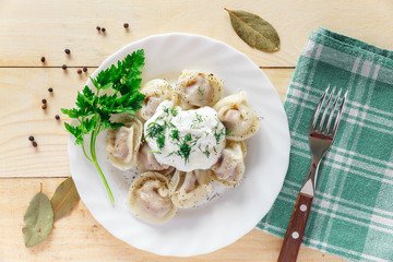 Plate with boiled dumplings served with parsley and sour cream