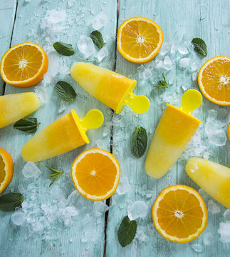 Home Made Orange Popsicles On Turquoise Wooden Surface