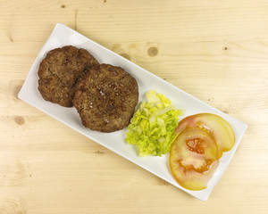 Hamburgers in a plate on wooden background - top view