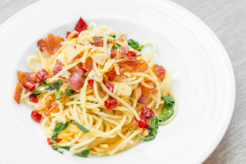 Spaghetti with fried crispy bacon and chili fried basil leave hot and spicy food delicious international cuisine in Thailand style