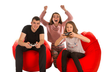 Young happy people are enthusiastic about playing video games while sitting on red beanbag chairs