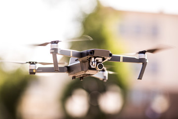 drone quad copter with high resolution digital camera flying hovering in the blue sky over the city