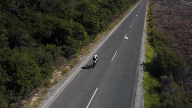Aerial view of a male cyclist riding a bicycle along a scenic road.
