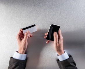 m-commerce with businessman hands holding credit card and phone