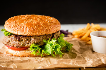 Classic american hamburger with beef and tomato sauce on dark background. Tasty food