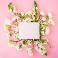 Frame of white flowers and paper card isolated on pink background. Flat lay. Top view