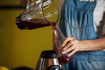 Mid-section of female staff preparing a juice