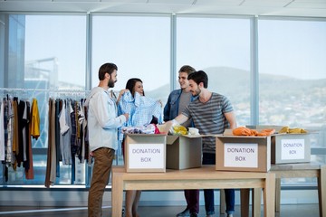 Creative business team sorting clothes in donation box