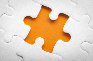 Completing final task, missing jigsaw puzzle pieces and business concept with a puzzle piece missing in the middle of the board on orange background and copy space
