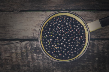 Black currants pot closeup on rustic wood background