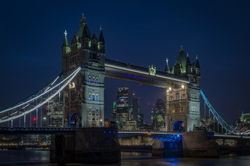 Tower bridge at night and the skyscrapers of the City of London in the background in England, UK
