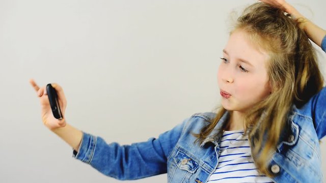 Happy little girl taking selfie with mobile phone.
